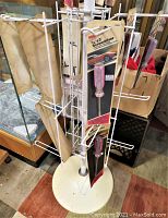 White metal display rack with screwdriver tool packaging hanging on hooks, round base visible.