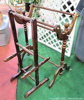 Side view of both vintage wooden furniture pieces showing turned spindle legs and curved base supports on green carpet with lattice background