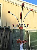 Close-up view of the top portion of the coat rack showing chrome hooks with round wooden balls, one ball missing.