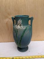 Front view of vase showing overall form, relief iris decoration and measuring tape indicating height