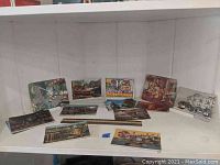 Photo showing a group of vintage postcards arranged on a white surface, including cityscapes and cultural images from mid-20th century.