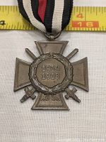 Front view of the bronze 1914-1918 war medal with two crossed swords, laurel wreath, and dated years, with measuring tape showing width.