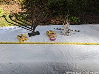 Both menorahs displayed with measuring tape and matchbox for scale on white cloth.