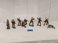 Front row image showing nine hand-painted old lead toy soldiers on a flat white surface, with a blue tape label reading '49' in front