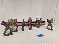 Wide shot of all six lead soldiers arranged in a row with a ruler behind for scale.