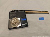 Photo of the pearl necklace coiled on a digital scale showing weight