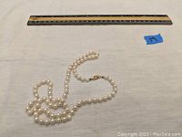 Pearl necklace coiled next to 12-inch ruler showing length and scale.