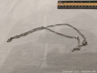 Full view of the sterling silver necklace laid flat showing chain length and style with a ruler above for measurement reference.