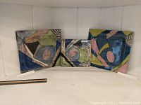 Front view of three decorative art dishes arrayed side by side showing their abstract colorful design. A ruler is placed beneath for scale reference.