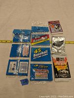 Photo of seven unopened vintage sports card packs including baseball and hockey cards stacked against a tape measure for size reference.
