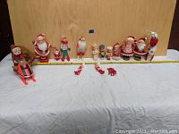 Wide shot of all vintage Christmas figurines and decorations arranged in a row, showing various sizes and styles.