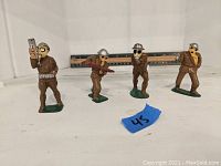 Four lead soldier figurines standing on shelf, showing entire lot and scale