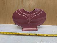 Frontal view of pink ceramic vase showing symmetrical Art Deco design and scale with measuring tape.