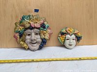 Two vintage ceramic masks made in Italy placed side by side, showing relative size.
