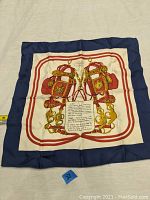 Full view of the handkerchief showing the blue border, cream center, and symmetrical red and gold harness design around a central text.