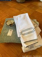 Green textured bathmat with two white towels, one towel showing brand RH, and small ceramic soap dish holding two soaps.