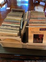Photo showing a large collection of CDs arranged vertically in two containers, featuring various classical, jazz, and other music albums.