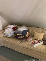 Fabric remnants and ribbon accessories piled on beige upholstered sofa