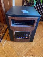 Full frontal view of the RCIN heater showing the rectangular vent and woodgrain finish.