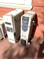 Photo shows two oil-filled radiator heaters side by side on a porch, the Welbilt heater on the left with visible rust and a deteriorated plug, the Pelonis heater on the right with control panel details.