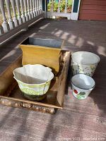Photo showing five planters including metal tray and rectangular metal planter along with three ceramic planters with floral designs.