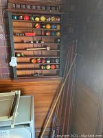 Full view of wooden cue and ball rack with balls, accessories and leaning cues