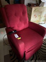 Front view of the red power recliner chair showing the tufted back and arm with slight wear, control remote visible.