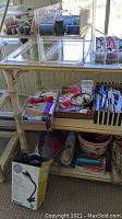 Wide view of sewing notions on shelves showing multiple boxes of buttons, spools of thread, lace pieces, scissors, and other sewing tools
