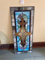 Full front view of rectangular stained glass window panel with fleur-de-lis design.