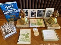 Photo showing Janet Evanovich book, two musical angels, black and white dog photos, greeting cards with floral designs, and small book with wildflower illustration.