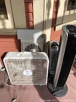 Square window fan, adjustable double window fan, black Holmes tower fan and white ceramic heater on porch floor, untested condition.