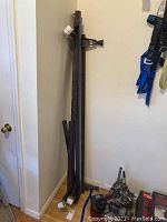 Multiple angles of dark metal bed frame parts leaning against a white wall, showing caster wheels and structural components