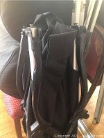 Folded sleeping cot frame with black metal legs and fabric sections packed together