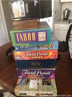 Stack of eight board games showing titles and worn condition in a kitchen setting.