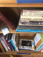 Two wooden shelves filled with books ranging from coffee table to smaller formats, showing titles on art, history, dreams, and botanical subjects.