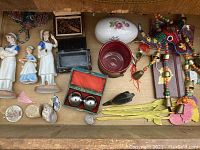 Photo shows vintage porcelain nurse figures in white and blue, small decorative boxes, colorful beaded elephant figurine, small Buddha and animal figurines, and various small decorative objects.