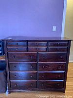 Front view of the dark wooden dresser showing eleven drawers with round wooden knobs.
