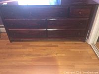 Full front view of the wooden dresser showing six drawers and scratches on surface.