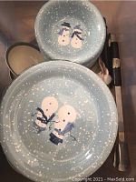 Close-up of two bowls with snowman design on speckled light blue ceramic.