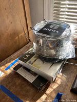 Aozita stackable lunch pail packaged in plastic wrap on wooden surface with other boxed items underneath