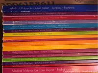 Spine view of multiple colorful nursing education workbooks on various case reports in legal nurse consulting.