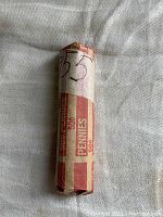 Paper-wrapped roll of unsearched wheat pennies labeled as 1955 coins.