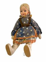 Front view of antique cloth doll sitting, showing blue polka dot dress with brown trim and headscarf.