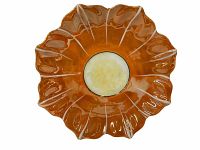 Top view of a flower-shaped ceramic plate with an orange glaze and a yellow center.