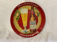 Front side of the round metal tray with Budweiser bottle, beer glass, barley and hops design on red background.