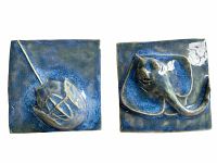 Pair of blue glazed ceramic tiles with raised relief sea creatures, horseshoe crab and stingray, displayed together.