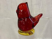 Front view of the red blown glass cardinal paperweight, showing its shape and color.