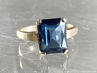 Front view showing the large rectangular blue stone with faceted cuts and gold band