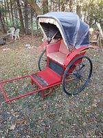 Left side view showing red wooden shafts, metal wheel and canvas canopy
