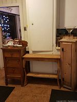 Three wood furniture pieces grouped together in room: medium antique cabinet, long table, and tall pine cabinet